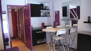 A compact kitchen with a dining area, a microwave, a coffee maker, and a small refrigerator.