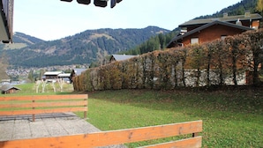 A wooden bench in a park with a view of a mountain and houses.