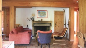 A cozy living room with a fireplace, wooden furniture, and a framed artwork on the wall.