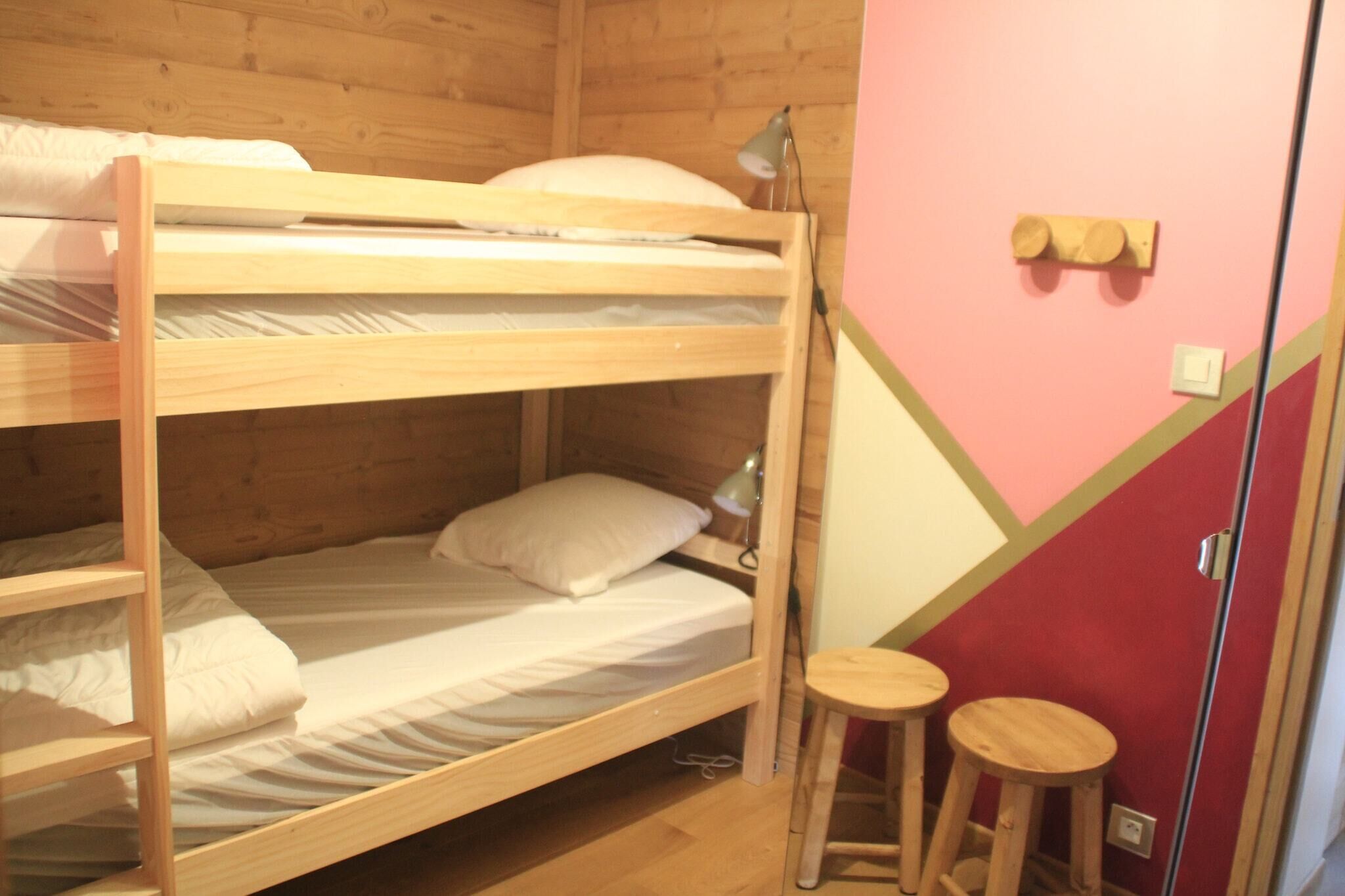 Habitació amb lliteres, un escriptori i dos tamborets.