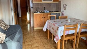 Une cuisine compacte avec des meubles en bois, un four à micro-ondes et un coin repas comprenant une table et des chaises.