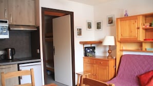 A compact living space with a kitchenette, a dining area, and a seating area with a sofa. - Studio in Portes du Soleil near Gondola (Châtel)