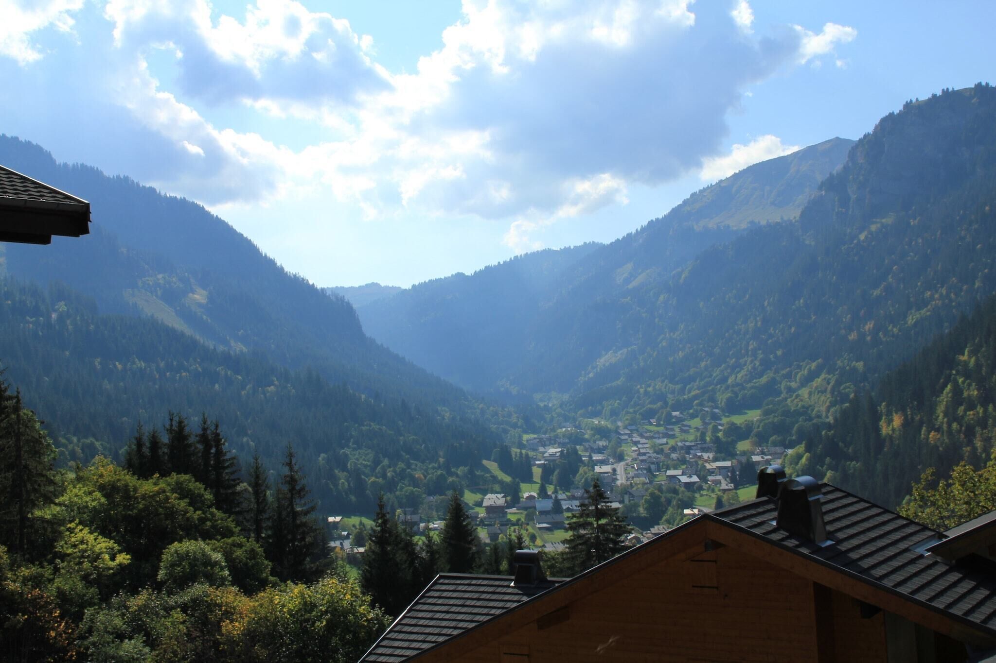 A valley with a town nestled among mountains, surrounded by dense forests.