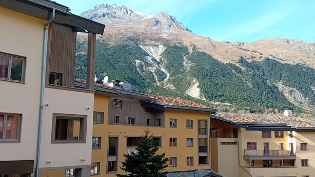 Un edificio de varios pisos con balcones y vista a la montaña.