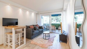 Un salon moderne avec un téléviseur, un canapé, une table basse et un grand miroir.