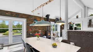 Een moderne keuken met een groot eiland, hangende verlichting en een stenen muur.