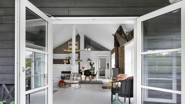 Een ruime binnenruimte met een hoge plafond, een eethoek en een gezellige zithoek.