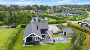 Een woonwijk met moderne huizen, een verzorgd gazon en een helder uitzicht op de zee op de achtergrond.