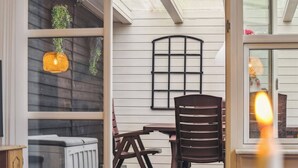 En åben patio med et bord, stole, en radiator og hængende planter.