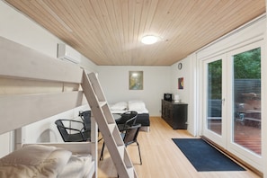 Une pièce comprenant un lit, un bureau avec une chaise, une échelle, un petit meuble et une grande fenêtre.