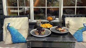 A table set with plates of food, a coffee mug, and a decorative bowl with an orange.