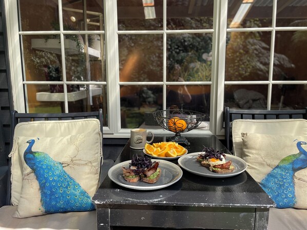 A table set with plates of food, a coffee mug, and a decorative bowl with an orange.