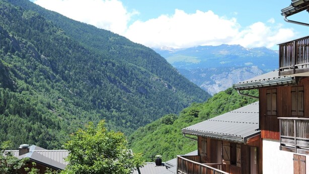 A traditional wooden building with a sloped roof, surrounded by lush green mountains and a clear blue sky. - Mountain view apartment in Orelle (Orelle)