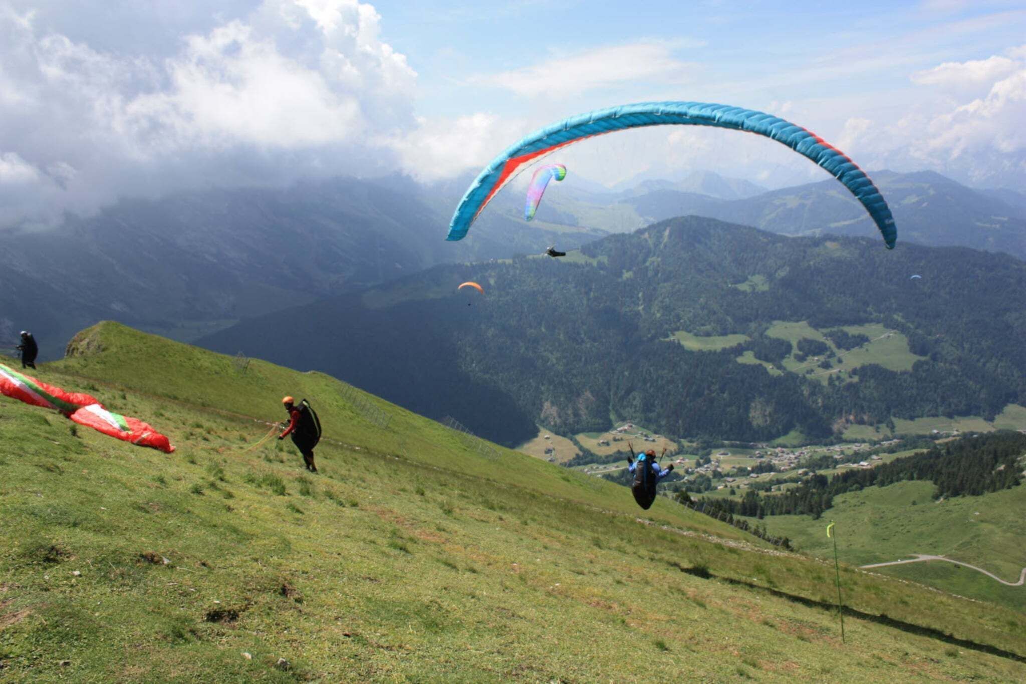 Un paysage montagneux où l'on voit une personne se préparer à s'élancer en parapente.