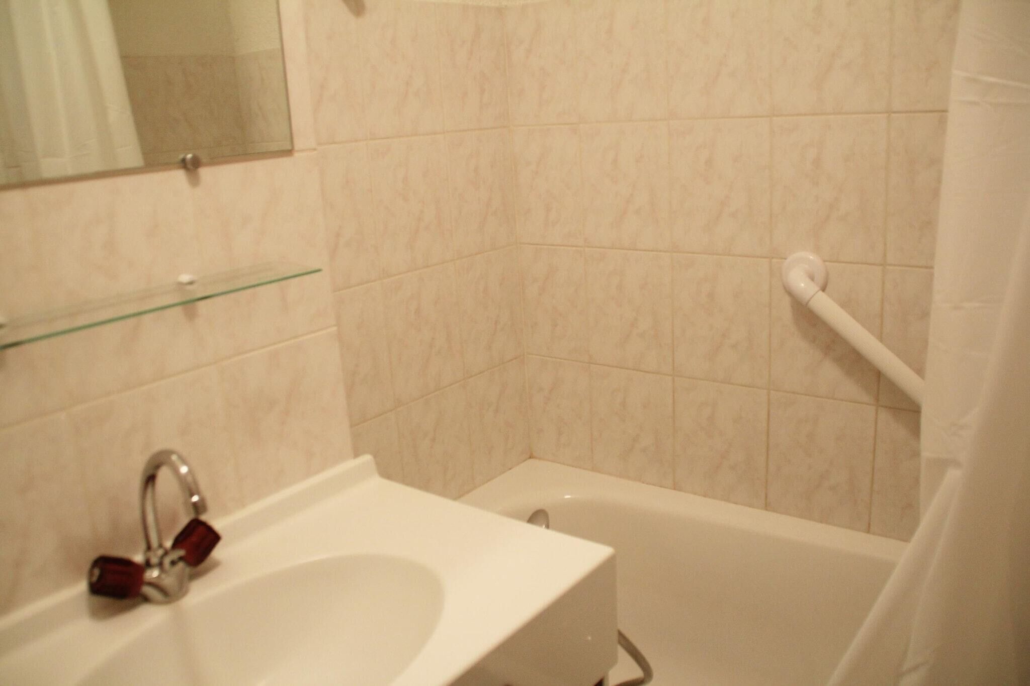 Un bagno con lavandino, specchio e vasca da bagno bianchi.