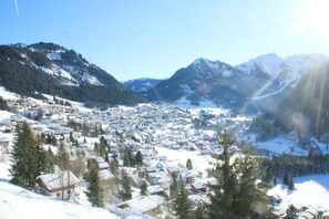 A snow-covered village with houses, trees, and mountains in the background.