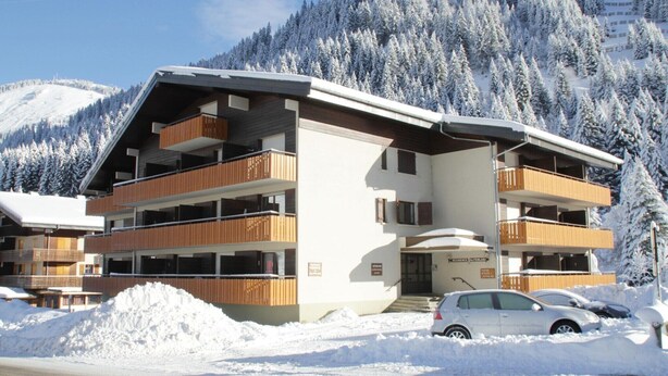 A multi-story building with balconies, a ski resort in the background, and snow-covered surroundings. - Studio in Châtel near Portes du Soleil Ski Area (Châtel)