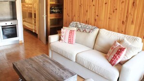 A cozy living room with a white sofa, a wooden coffee table, and a wooden wardrobe. - Studio in Châtel near Portes du Soleil Ski Area (Châtel)
