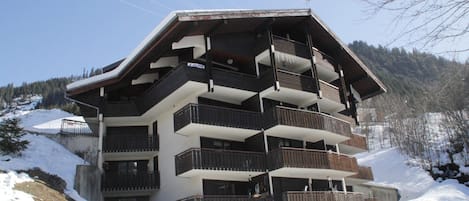 A multi-story hotel with balconies, located in a snowy mountainous area.