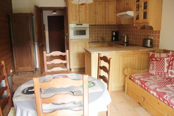 A compact kitchen with wooden cabinets, a built-in oven, and a small countertop. - Apartment in Châtel near Ski Lifts & Views (Châtel)