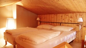 Um quarto com painéis de madeira, uma cama, duas luminárias de cabeceira e uma janela.