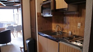 Uma cozinha compacta com armários de madeira, uma pia e um fogão.