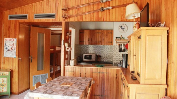Un interior de madera con una mesa de comedor, zona de cocina y armarios.