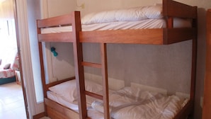 Una cama litera con ropa de cama blanca y estructura de madera.