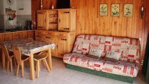 Una cocina acogedora con armarios de madera, una mesa de comedor con sillas y un sofá estampado.