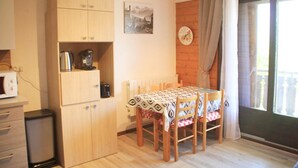 Une cuisine compacte avec des meubles en bois, une machine à café et une table recouverte de nappes à motifs.