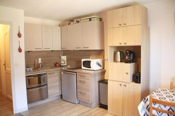 A compact kitchen with white cabinets, a microwave, a coffee maker, and a dishwasher. - Apartment in Vonnes with Stunning Mountain Views (Châtel)