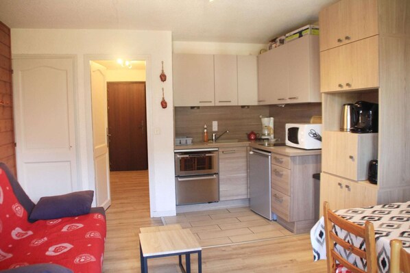 A compact kitchen with stainless steel appliances, a microwave, and a coffee maker.