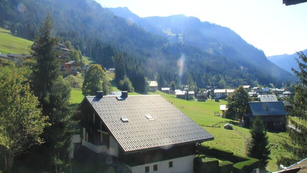 Un village rural avec des maisons et une chaîne de montagnes en arrière-plan.