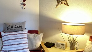 Une chambre confortable avec un lit, des oreillers, une lampe de chevet, une radio et une décoration en forme d’étoile sur le mur.