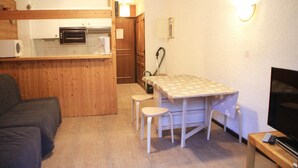 A compact living space with a kitchenette, a dining area with a table and two stools, a sofa, and a television. - Apartment for 3 people in Chatel (Châtel)