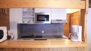 A compact kitchen with a built-in microwave, a coffee maker, and wooden cabinetry. - Apartment for 3 people in Chatel (Châtel)