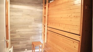 A room with a wooden floor and a wooden wall. There is a small wooden stool in the corner.