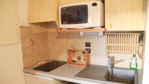 A kitchen with a microwave, a wooden spice rack, a coffee maker, and a sink.