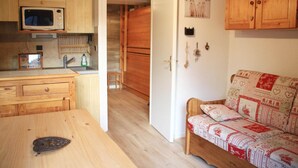 A compact kitchen with a microwave, wooden cabinets, and a small dining table.
