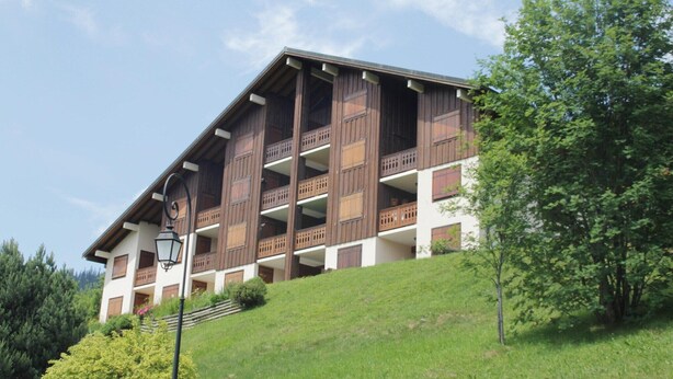 A multi-story building with balconies, a sloped roof, and a lamp post. - Apartment in Petit Châtel near Cable Car (Châtel)