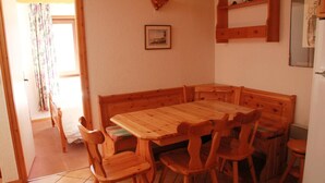 A wooden dining table with six chairs, a wooden bench, and a small shelf above the table. - Apartment in Petit Châtel near Cable Car (Châtel)
