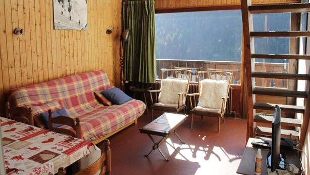 Une pièce chaleureuse avec un canapé à carreaux, deux fauteuils, une petite table et une grande fenêtre donnant sur une montagne.