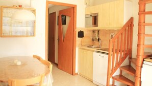 Una cucina compatta con mobili in legno, forno integrato e lavastoviglie.