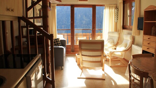 Un ampio soggiorno con una scala in legno, un divano, una poltrona e un tavolo da pranzo.
