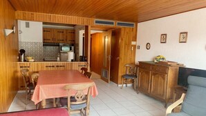 Una habitación acogedora con una mesa de comedor de madera, sillas, un sofá y un televisor.