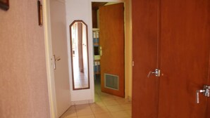 Un pasillo con una puerta de madera, una puerta blanca y un espejo en la pared.