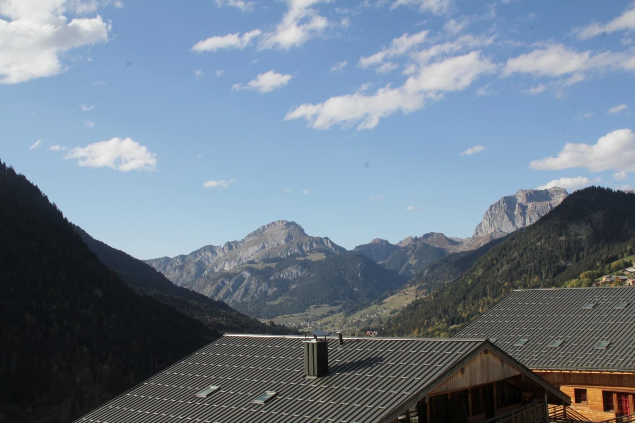 Un paysage de montagne avec un ciel dégagé et un bâtiment doté d’un toit en pente.