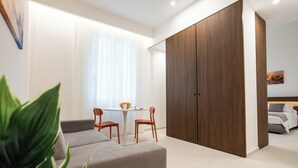 A modern room with a large wardrobe, a dining table with chairs, and a sofa. - Nora's Suites (Palermo)