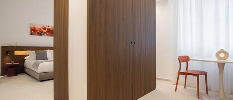 A bedroom with a bed, a wooden wardrobe, a bedside table, a chair, and a table with a ring on it.