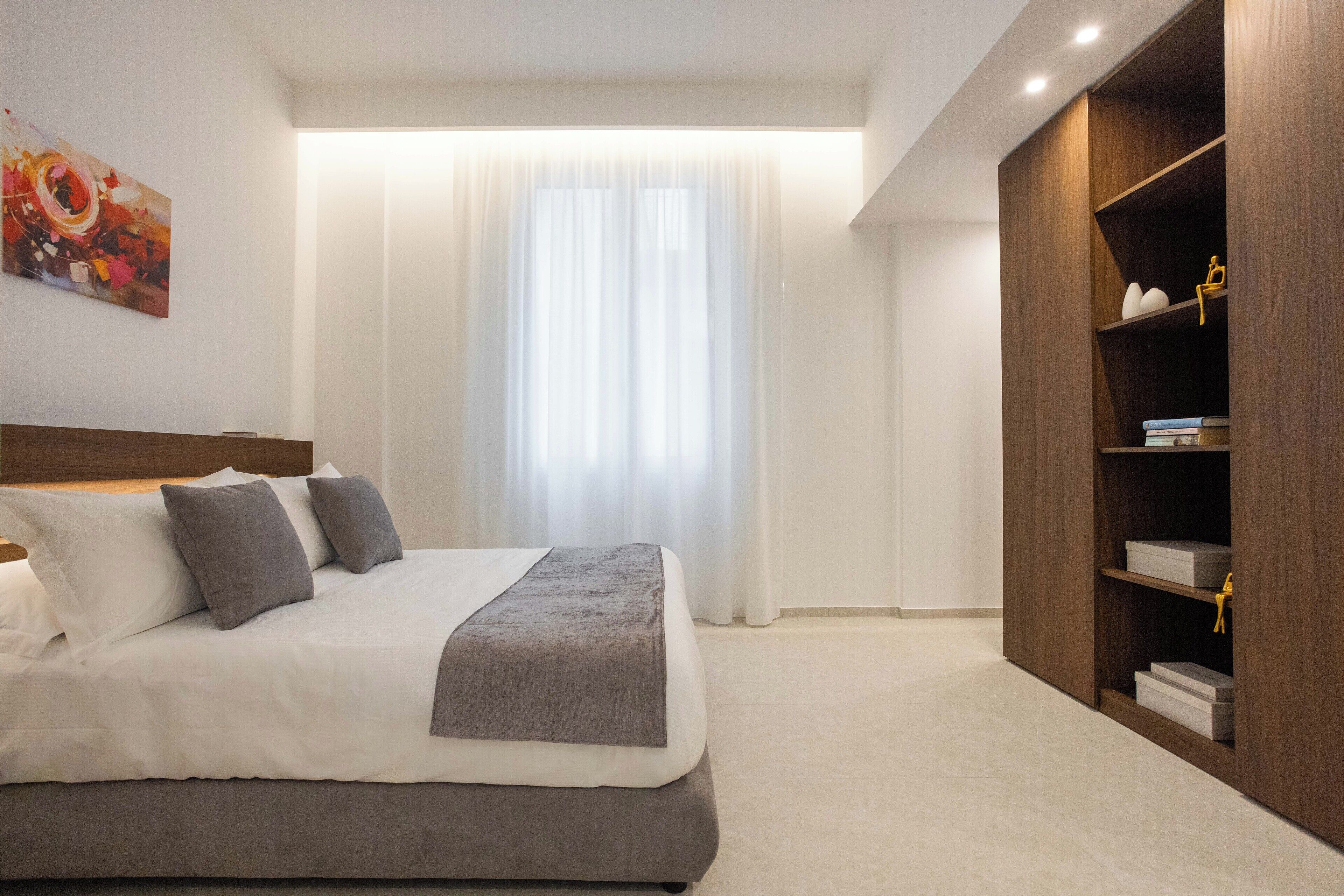 A modern bedroom with a large bed, a wooden wardrobe, and a painting on the wall.